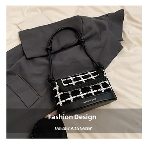 Close-up of black and white tweed bucket bag with leather trim and knotted shoulder strap