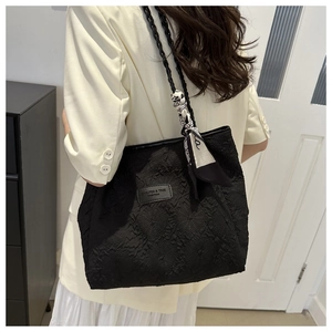 Detail of black pleated tote bag featuring woven handle and decorative floral silk scarf