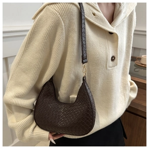 Detail of dark brown woven texture hobo bag with gold hardware worn over beige sweater