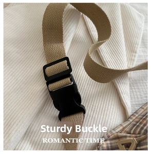 Macro shot of durable black plastic buckle and khaki nylon strap on plaid bag