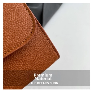 Close-up of litchi textured leather handbag showing premium stitching and caramel brown finish