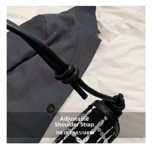 Detail of adjustable knotted leather strap on black and white plaid woven shoulder bag