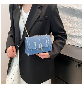 Detail of light blue denim crossbody bag with golden chain and metallic buckle