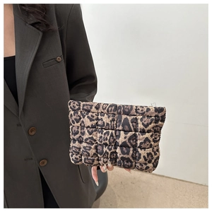 Close-up of leopard print quilted clutch bag with metal zipper detail held by model