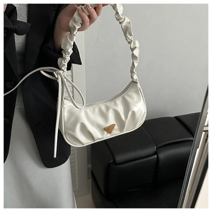 Detail of white pleated handbag featuring glossy leather and gold triangle metal plaque