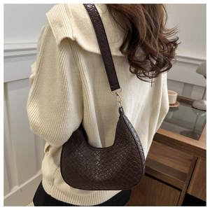 Detail of dark brown woven crescent bag with embossed wide shoulder strap texture