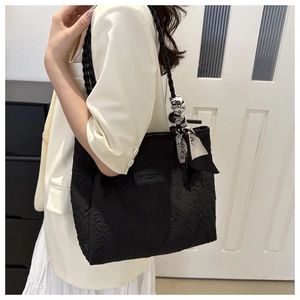 Detail of black tote bag with embossed floral texture and decorative printed silk scarf