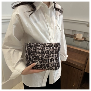 Detailed view of hand-held leopard print quilted clutch bag with brown leopard pattern