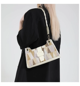 Close-up of geometric patchwork texture and wide strap on minimalist shoulder bag