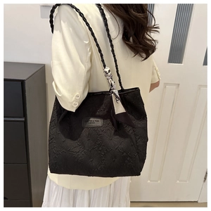 Detail of black textured tote bag with woven shoulder straps and decorative printed silk scarf