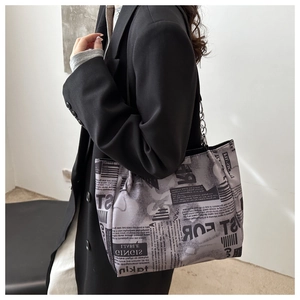 Detail of aesthetic newspaper print tote bag with silver metal chain shoulder strap