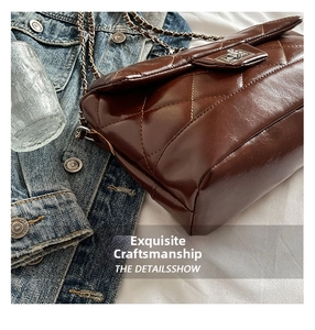 Detail of dark brown quilted faux leather bag with silver twist lock and chain strap