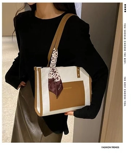 Detail of white textured tote bag with brown pocket, leather straps and leopard scarf
