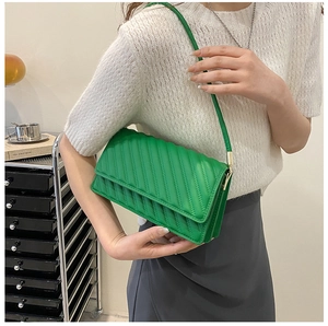 Détail du sac à bandoulière matelassé vert avec boucles dorées dans un décor citadin
