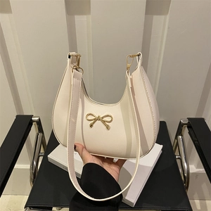 Cream crescent hobo bag with gold bow buckle and leather strap for women