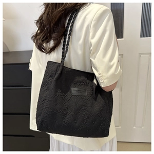 Detail of black textured tote bag with rope handles and logo patch on model