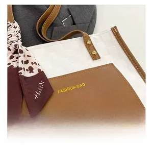 Detail of white checkered tote bag with brown leather pocket and silk scarf handle