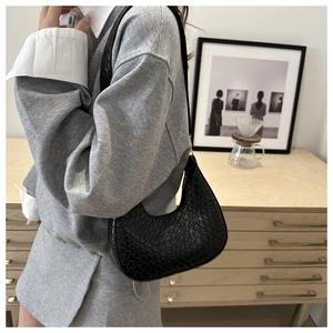 Fashionable black crescent shoulder bag with crocodile pattern texture on a model
