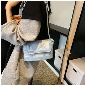 Detail of light blue quilted bucket bag with adjustable strap worn by model
