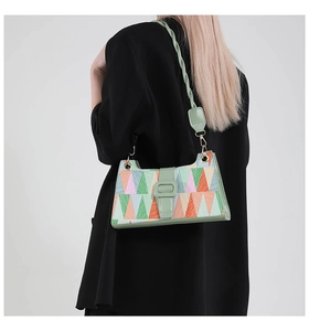 Detail of geometric shoulder bag featuring colorful triangle patterns on black blazer