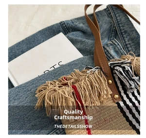 Detail showing woven texture with plaid patterns and fringe trim on the tote bag