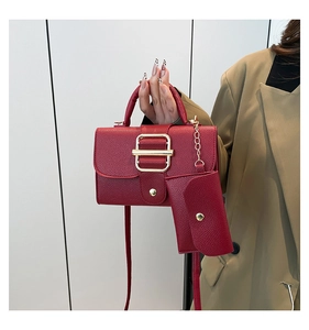 Detail of red lychee pattern handbag with golden buckle and matching small pouch