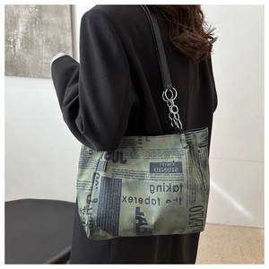 Close-up of dark green newspaper print tote bag with silver metal chain and strap