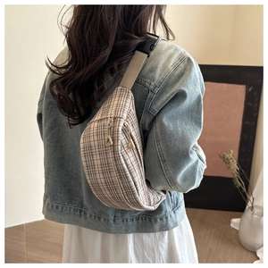 Detail of plaid waist bag featuring a dual zipper design and sturdy plastic buckle strap