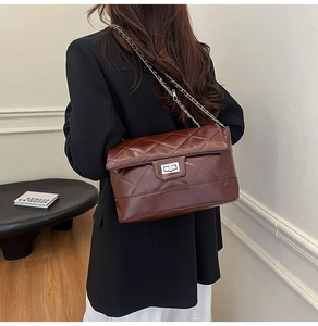 Detail of dark brown quilted crossbody bag with silver twist lock and chain strap