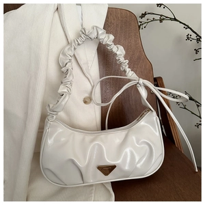 Detail of white glossy ruched shoulder bag with a gold triangle logo on a suit