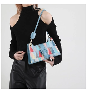 Detail of color-block baguette bag featuring geometric patterns and woven light blue strap