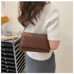 Gros plan d'un sac à bandoulière matelassé marron avec détail d'anneau en métal doré