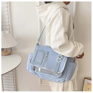 Detailansicht der hellblauen Kuriertasche mit Klarsichtfach und Netzfach am Model