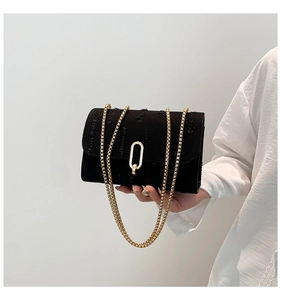 Detail of distressed black denim crossbody bag with gold buckle and chain strap
