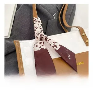 Close-up of leopard print scarf wrapped on the handle of a white tote bag with tan strap