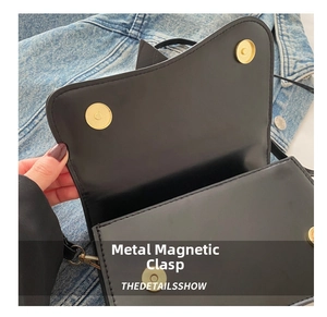 Dettaglio della chiusura magnetica dorata su borsa in pelle nera con cuciture di precisione