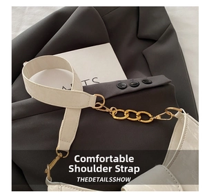 Detail view of a white leather shoulder strap connected to a gold chain on a blazer