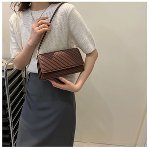 Détail du sac bandoulière matelassé marron foncé avec coutures et fine lanière