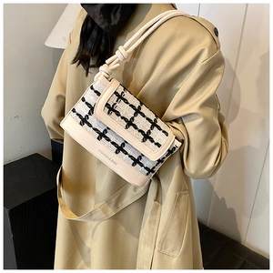 Detail of tweed quilted bucket bag with beige leather trim and knot shoulder strap detail
