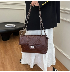 Detail of chocolate brown quilted chain bag with silver twist lock and leather strap