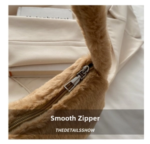 Close-up of a smooth silver metal zipper on a brown plush handbag detail view