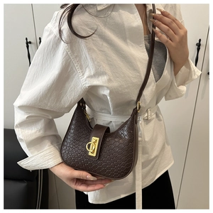 Detailed close-up of dark brown woven leather crescent bag with golden circular buckle