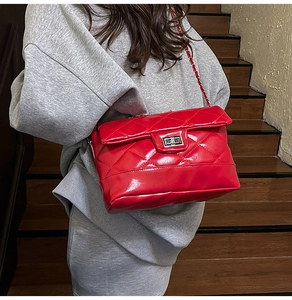 Detail of red quilted chain bag with metallic turn-lock closure on model