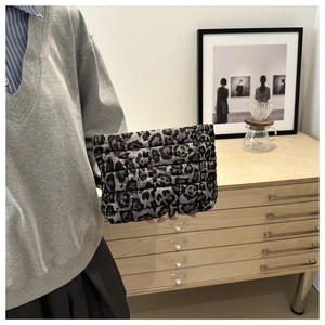 Close-up of leopard print quilted clutch bag held in hand for size demonstration