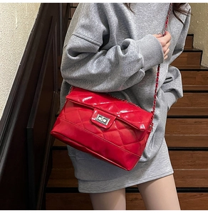 Macro detail of red quilted leather crossbody bag with chain strap and metal clasp