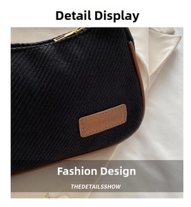 Close-up of woven black shoulder bag with brown leather trim and golden zipper detail