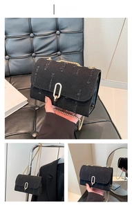 Detail of black denim crossbody bag with distressed edges and gold chain strap
