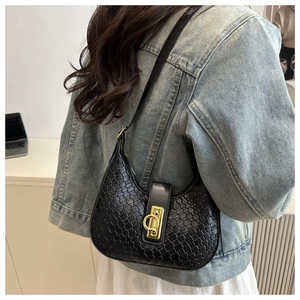 Detail of black woven hobo bag with gold circular buckle and premium textured finish