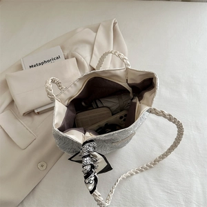 Minimalist beige tote bag with woven handles and silk scarf detail in a spacious top view
