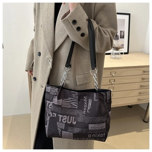 Dettaglio della borsa tote con stampa di giornale e catena argentata per un look trendy